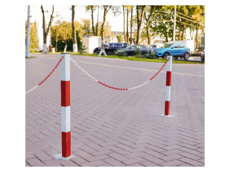 Červeno-biele zábranné stĺpiky s reťazou na ulici s zaparkovanými autami.