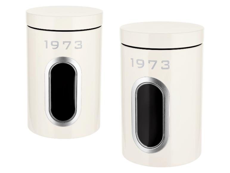 Dve krémové nádoby s nápisom „1973“ a okienkom na prezeranie obsahu.