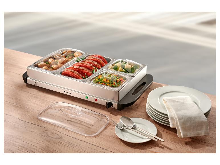 Nerezový ohrievač jedla s mäsom, zemiakmi a zeleninou na drevenom stole.