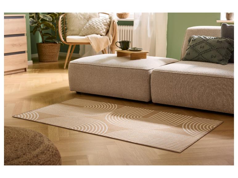 Obývacia izba s béžovou pohovkou, vzorovaným kobercom a dreveným nábytkom.