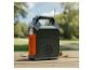 Prenosná elektráreň s baterkou, rádiom a USB portami na drevenom stole vonku.
