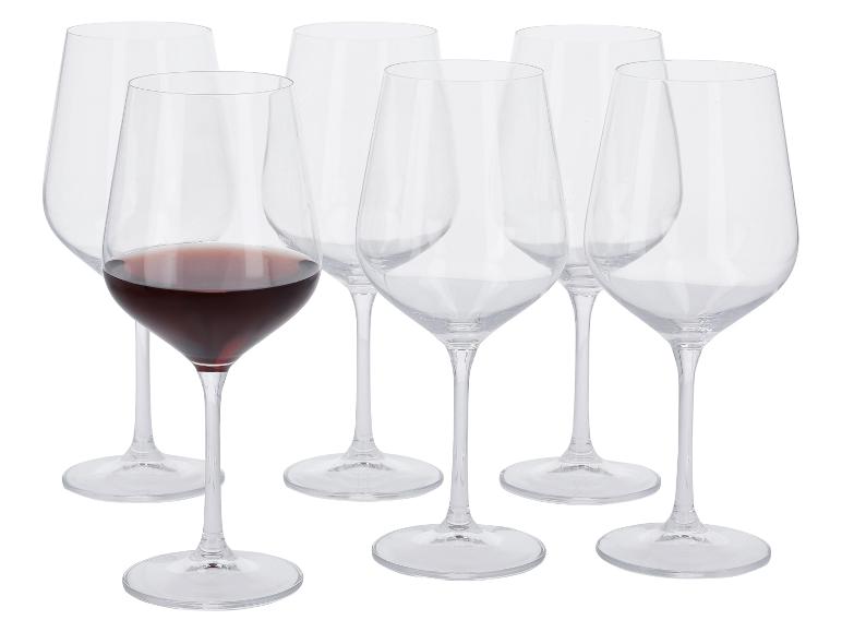 Šesť pohárov na víno, jeden naplnený červeným vínom, na bielom pozadí.