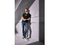 Muž v čiernom tričku a džínsoch, zeleno-bielych teniskách, opretý o stenu.