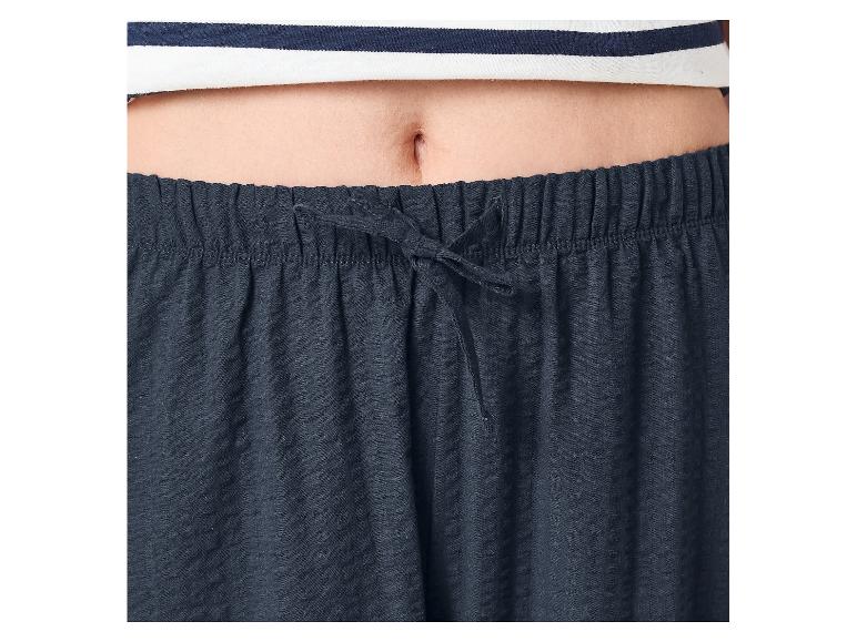 Brucho osoby v pruhovanom tope a tmavomodrých pyžamových nohaviciach so šnúrkou.