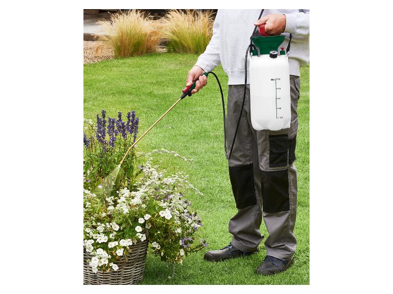 Osoba postrekuje rastliny v záhrade ramenným tlakovým postrekovačom.