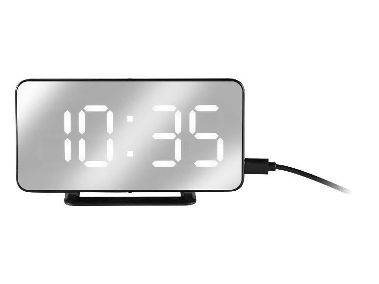 Digitálne zrkadlové hodiny zobrazujúce 10:35, s čiernym napájacím káblom.