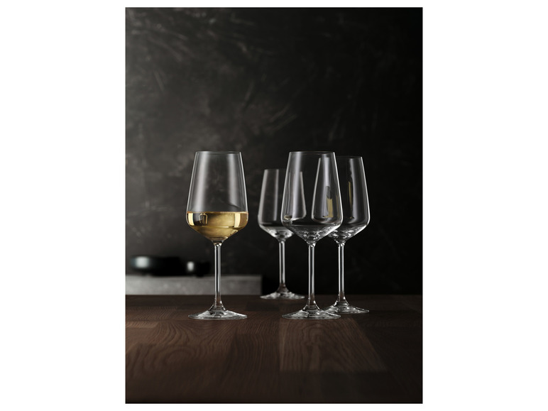 Tri poháre, z ktorých jeden s bielym vínom, na drevenom stole.