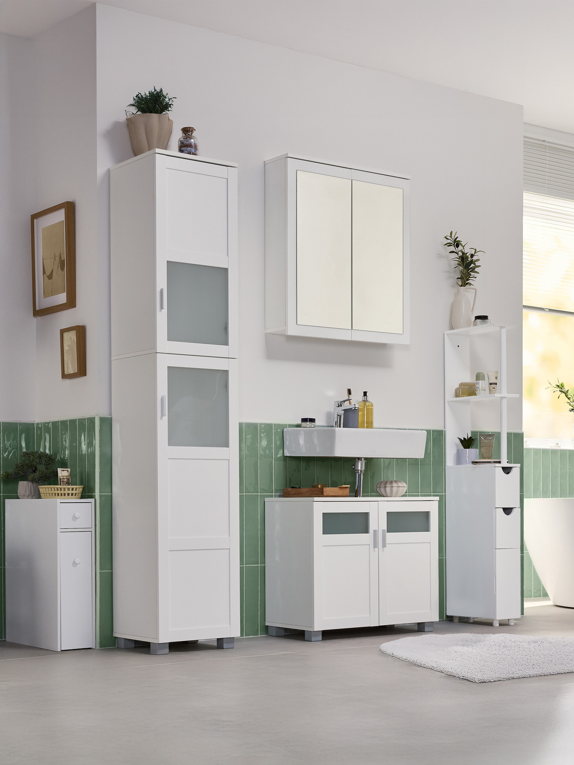 Kúpeľňa s bielymi skrinkami, umývadlom a zelenými obkladmi.