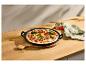 Zeleninová pizza v čiernej liatinovej panvici na drevenom stole s ľanovou utierkou.