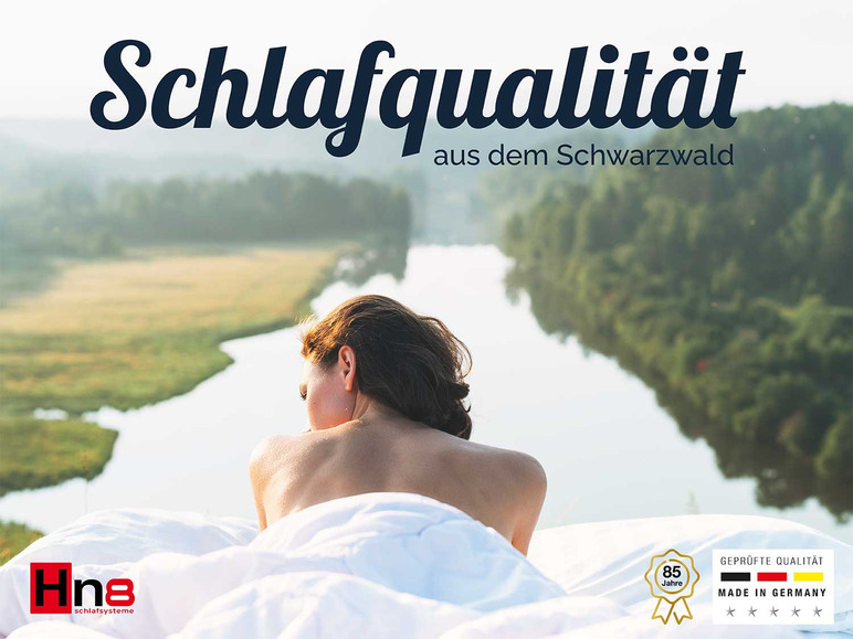 Žena v posteli s matracom Hno8 s heslom 'Kvalita spánku z Čierneho lesa'.