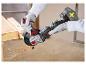 Osoba v rukaviciach reže medenú rúrku akumulátorovou uhlovou brúskou, vytvárajúc iskry.