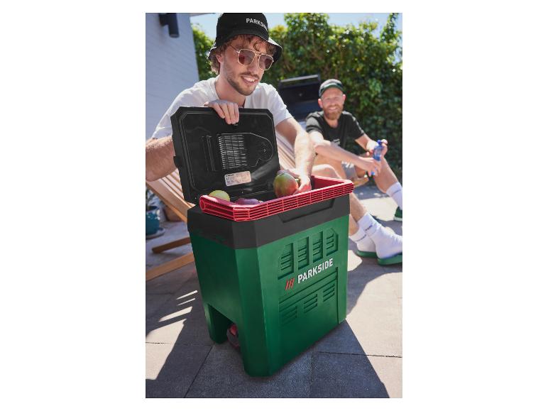 Dvaja muži vonku, jeden otvára zelený a čierny chladiaci box s ovocím vo vnútri.