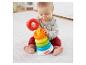 Dieťa sa hrá s farebnou vežou krúžkov Fisher-Price na bielom koberci.