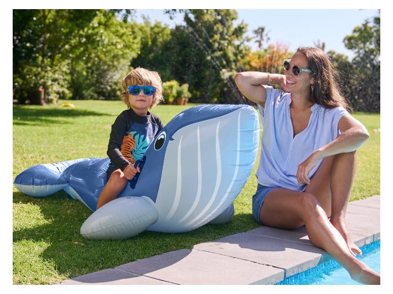 Dieťa sa hrá na nafukovacom veľrybom pri bazéne.