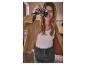 Žena v béžovej bunde a džínsovej sukni fotí starým fotoaparátom.