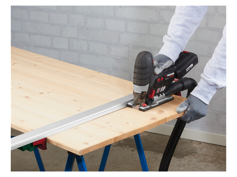 Pracovník používa pílku Parkside na rezanie dreva na pracovnom stole.