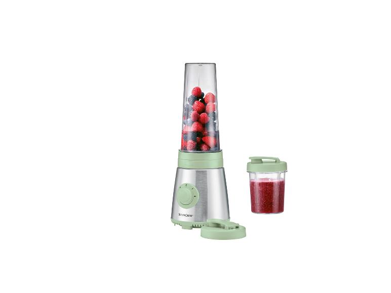 Strieborný mixér SilverCrest s bobuľami a pohárom smoothie.