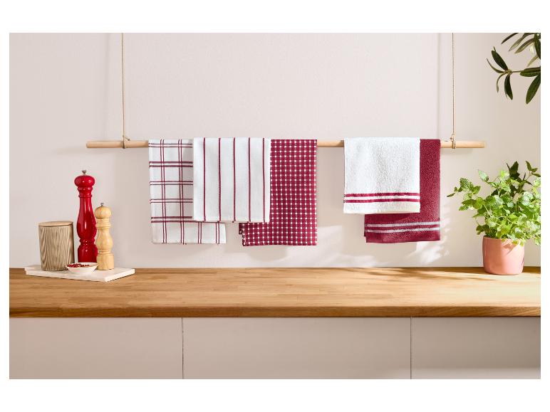 Červeno-biele kuchynské utierky visiace na drevenej tyči v kuchyni.