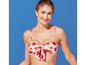 Žena má na sebe biele bikiny s červeným kvetinovým vzorom.