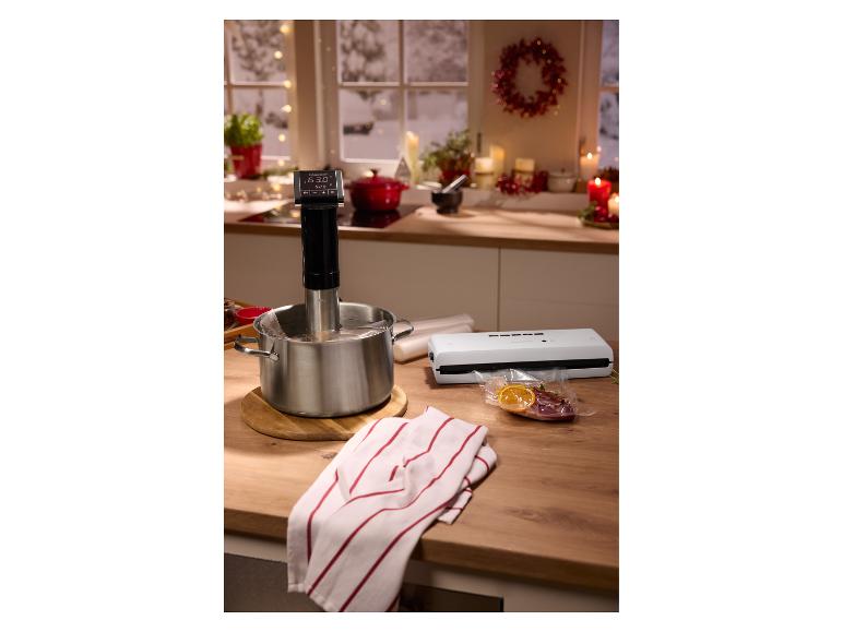 Sous vide varič v hrnci, vákuová zváračka a vákuovo balené jedlo na kuchynskej linke.