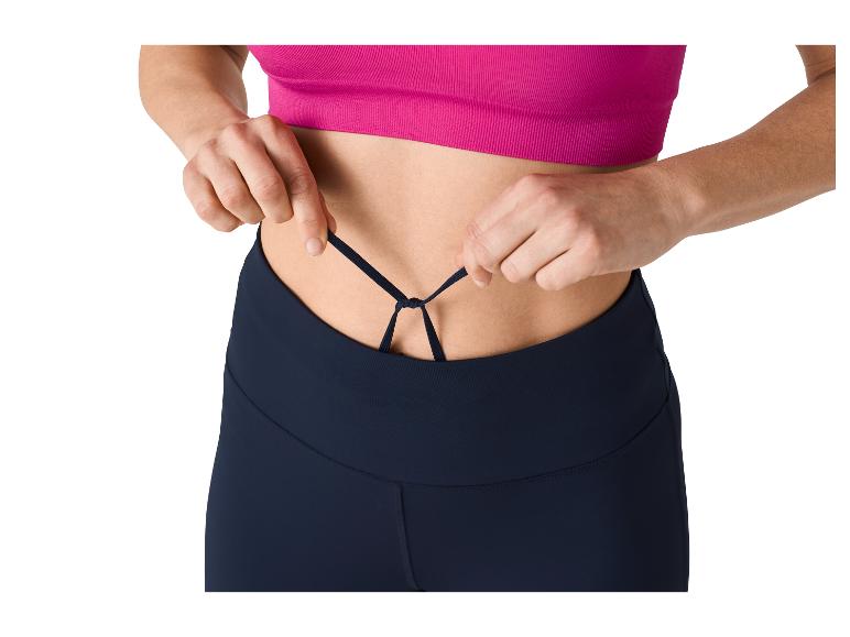 Žena si upravuje šnúrky na športových legínach a ružovom tope.