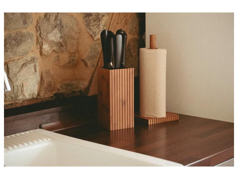 Drevený blok na nože a držiak na papierové utierky na kuchynskej linke.