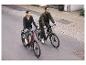 Pár jazdí na elektrických bicykloch po mestskej ceste.