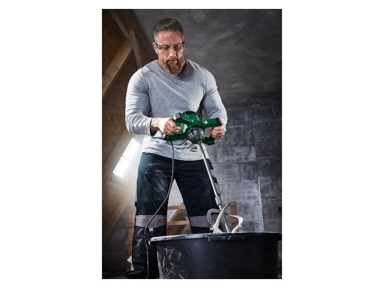 Muž používa elektrický miešač na miešanie malty.