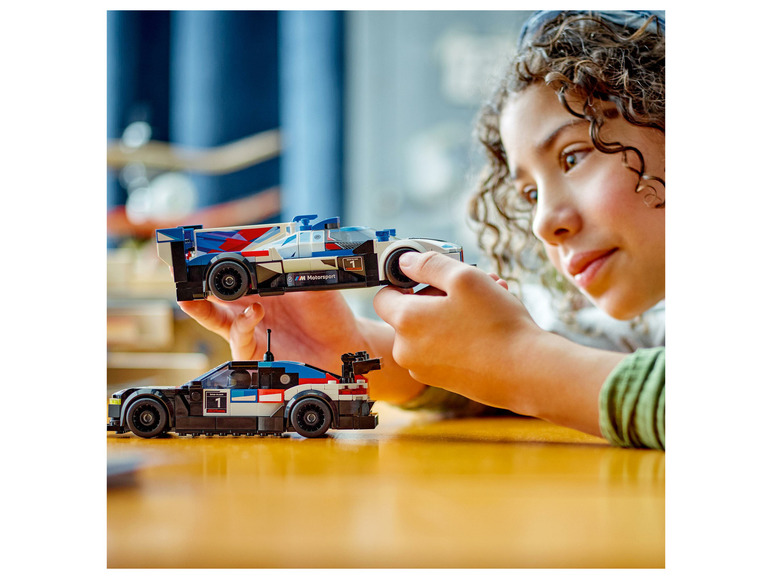 Dieťa si hrá s dvoma LEGO pretekárskymi autami, vrátane BMW M Motorsport.