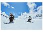 Dvaja ľudia lyžujú a snowboardujú na zasneženom svahu.