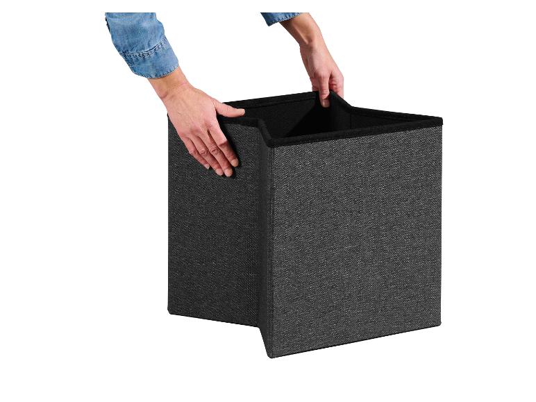 Ruky držia tmavosivý skladací úložný box, pripravený na použitie.