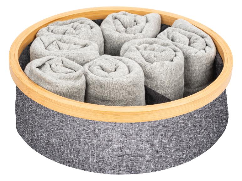 Zrolované oblečenie v sivom koši s bambusovým okrajom.
