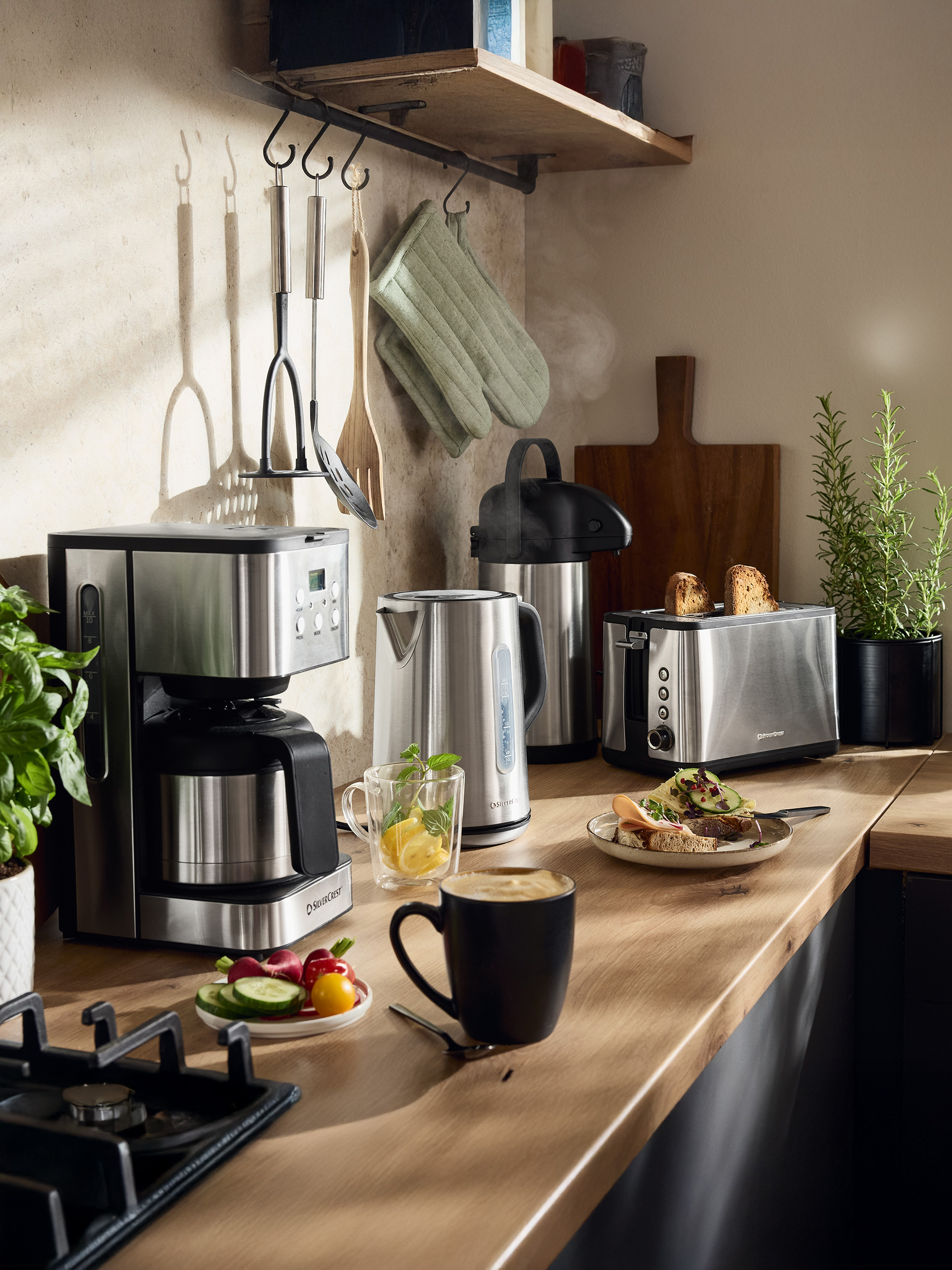Kávovar SilverCrest, rýchlovarná kanvica a hriankovač v kuchyni s jedlom a nápojmi.