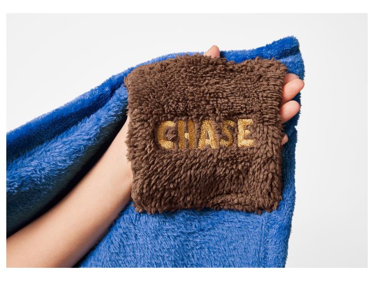 Modrá a hnedá deka s vyšívaným textom „CHASE“ v ruke