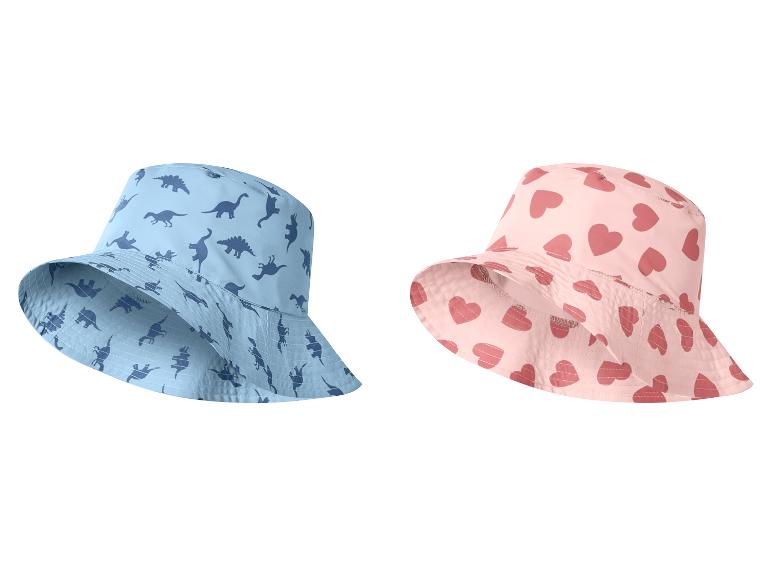 Dva detské klobúky: jeden modrý s dinosaurami a druhý ružový so srdiečkami.