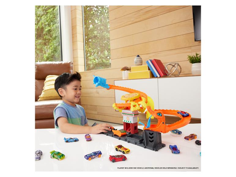 Chlapec sa hrá so súpravou Hot Wheels s drakom a mnohými autíčkami.