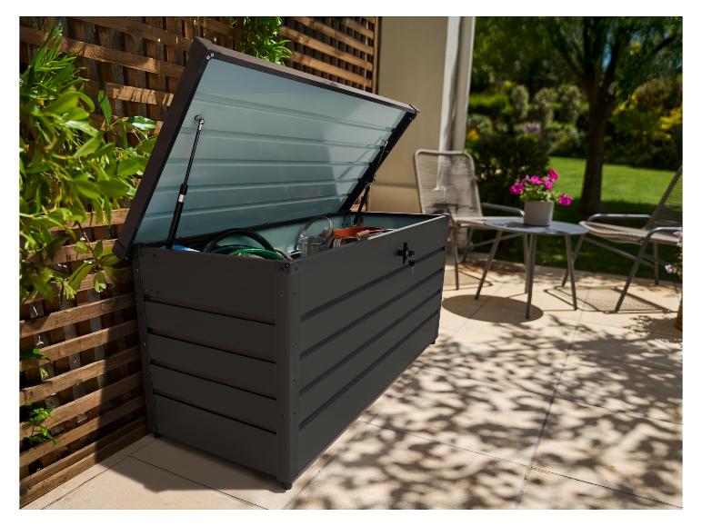 Tmavosivý vonkajší úložný box s otvoreným vekom, plný záhradného náradia, na terase.