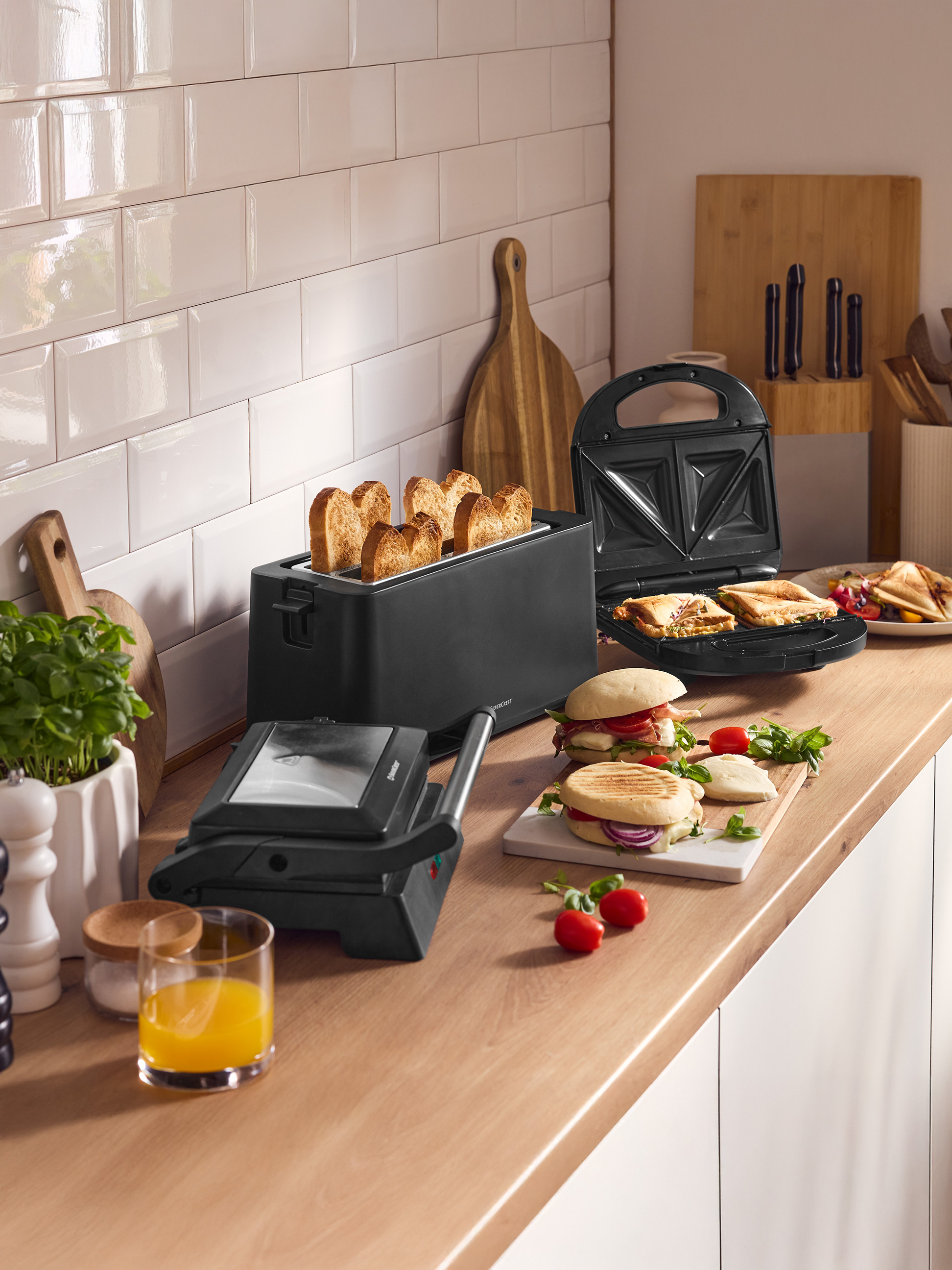 Kuchynská linka s hriankovačom, sendvičovačom a grilovacím lisom, pripravenými sendvičmi a džúsom.