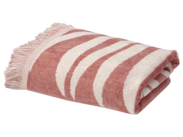 Zložená ružovo-biela plážová osuška so zebrovým vzorom a strapcami.