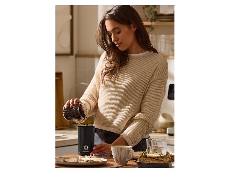 Žena sype kávové zrná do mlynčeka na kávu SilverCrest na kuchynskej linke.