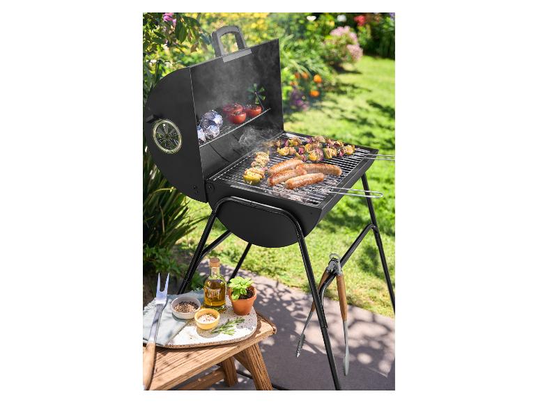 Gril na drevené uhlie s klobásami a špízmi v slnečnej záhrade.