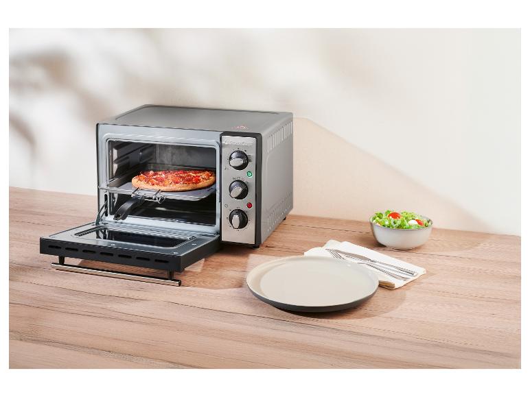 Mini rúra SilverCrest s pizzou vo vnútri, vedľa taniera a misky na šalát.