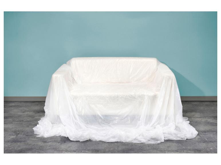 Pohovka pokrytá bielou plastovou fóliou pred svetlomodrou stenou