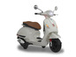 Biely skúter Vespa s hnedým koženým sedadlom.