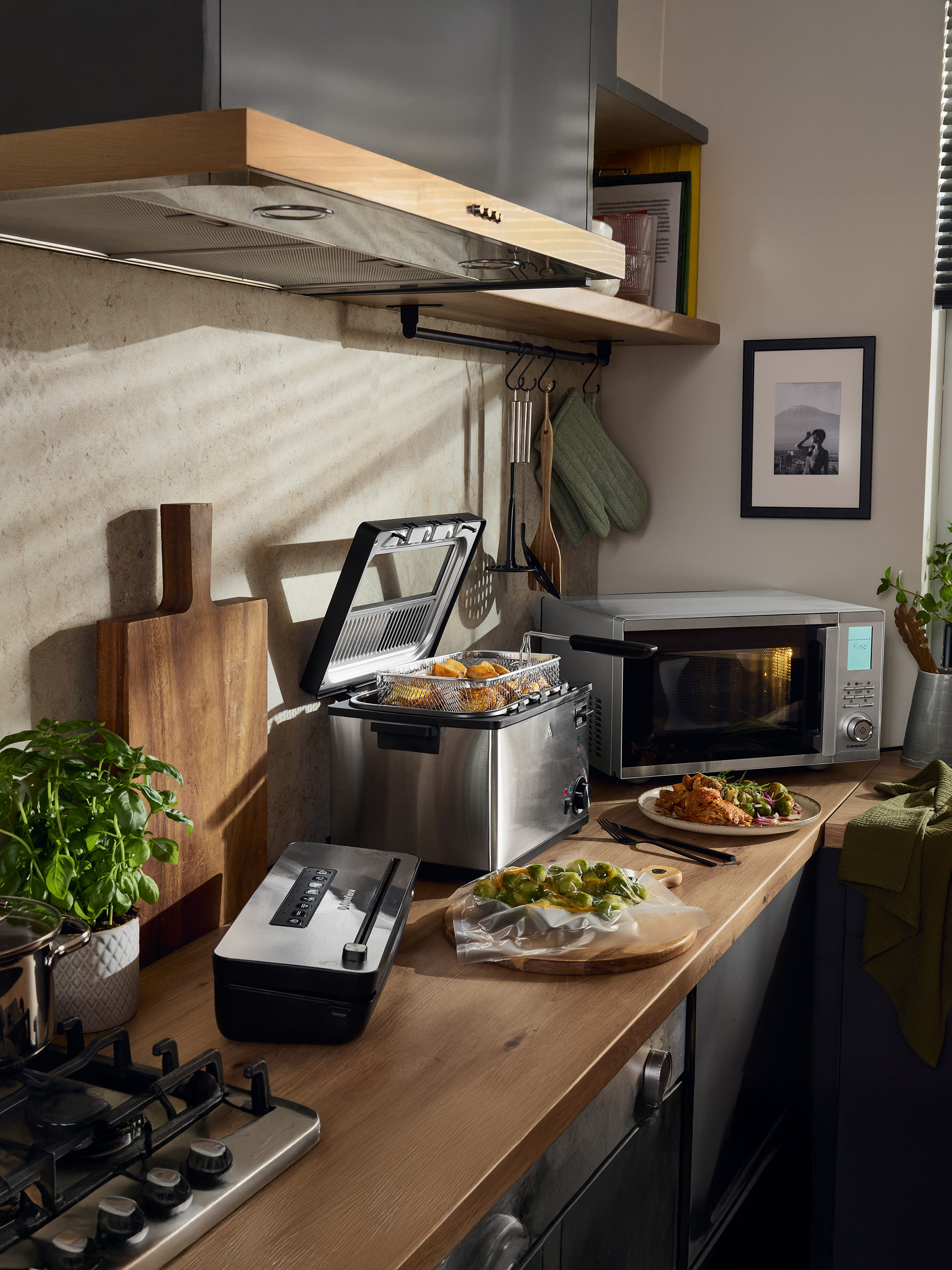 Kuchyňa s fritézou, mikrovlnnou rúrou SilverCrest, vákuovačkou a pripraveným jedlom.