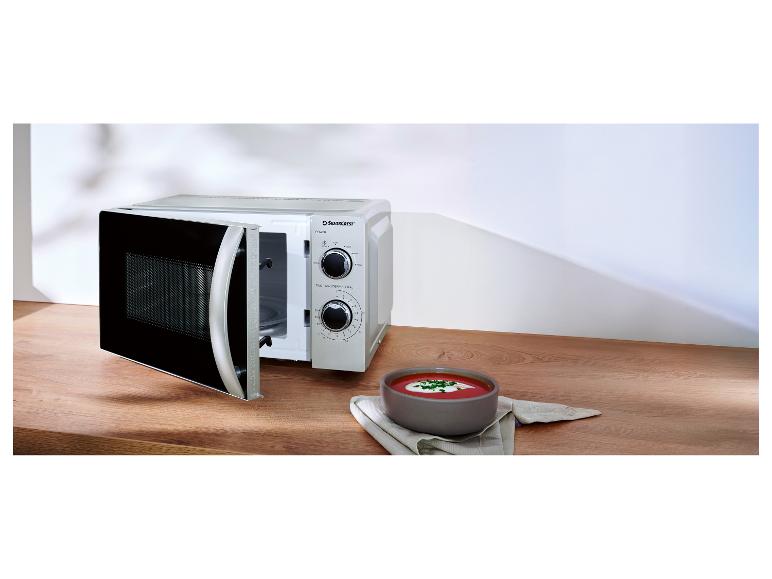 Mikrovlnná rúra Silvercrest s otvorenými dvierkami a miska polievky na drevenom stole.