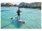 Muž pádluje na paddleboarde v tyrkysovej vode so skalnatým pobrežím v pozadí.