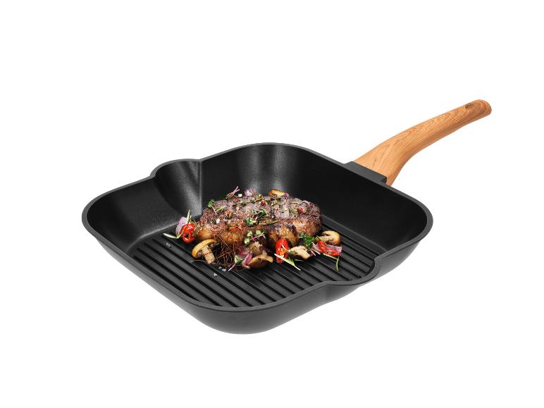 Grilovaný steak so zeleninou v čiernej štvorcovej grilovacej panvici s drevenou rukoväťou.