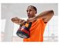 Muž v oranžovom tričku drží 10 kg kettlebell.