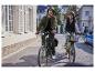 Dvaja ľudia jazdia na elektrických bicykloch v meste.